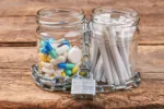 Cigarettes, pills, chain, wooden background. Jars with pills and cigarettes wrapped in metal chain on wooden background. Concept of tobacco cigarette addiction.