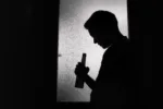 Silhouette of a man staring at a bottle