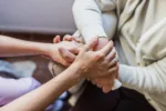 Close-up of nurse holding a patient's hands