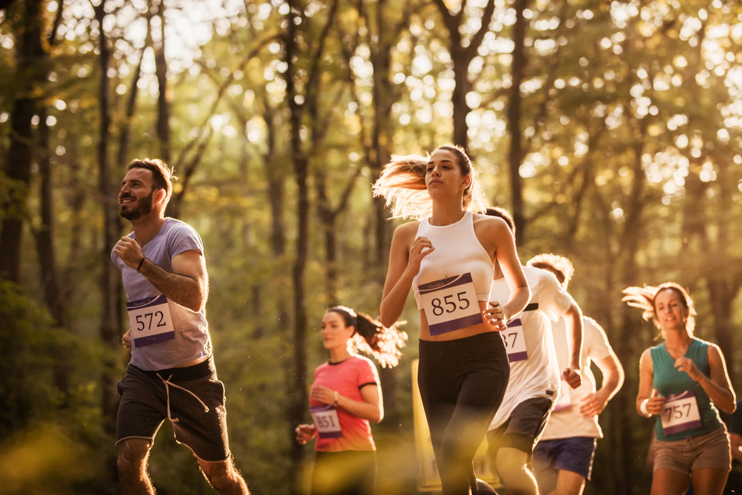 Group of marathon runners having a race through the forest.