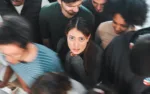 Shot of a young woman experiencing mental illness while being surrounded by people inside.