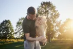 Man is embracing of therapy horse on meadow at sunset. Themes hippo therapy, care and friendship between people and animals.