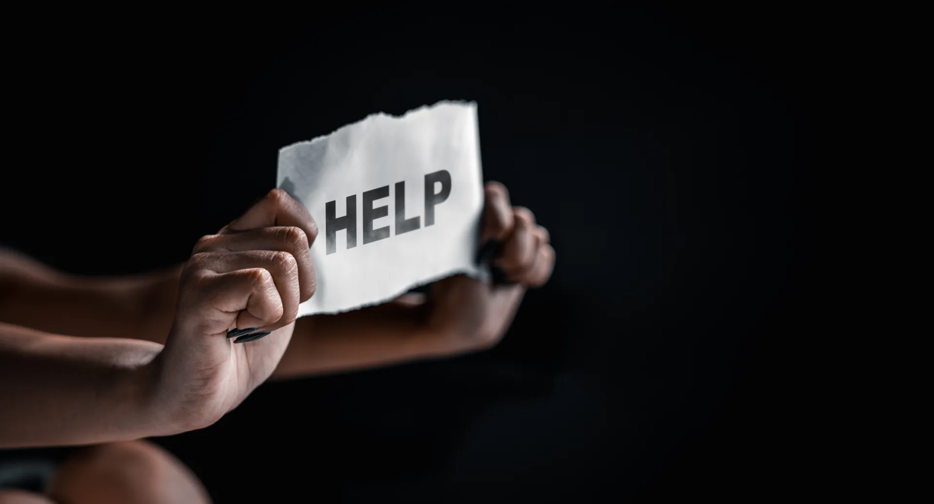 Woman holding paper with text asking for help.